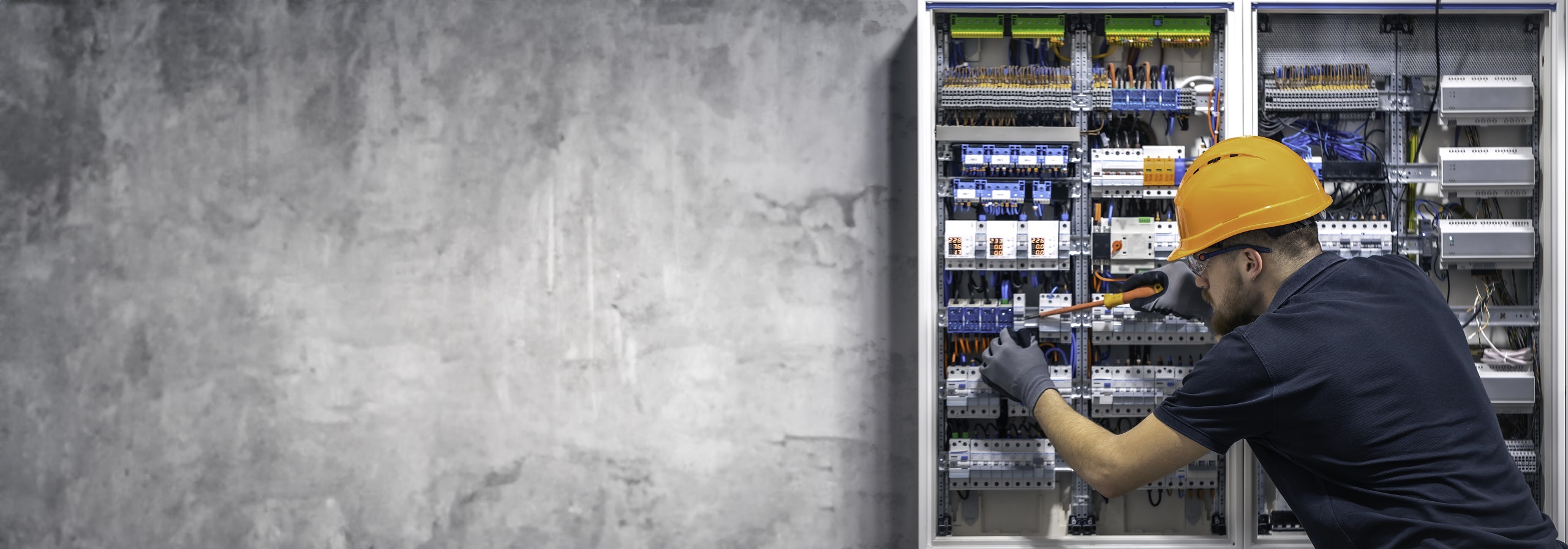 Home electrician working in switchboard with electrical connection cable, copy space.